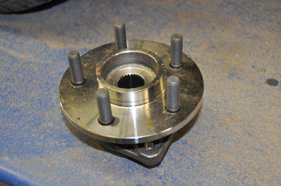 Wheel hub assembly with five wheel studs, resting on a blue surface