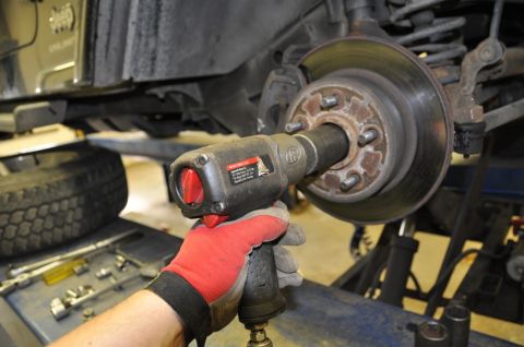 1996 Ford Bronco - A mechanic uses an impact wrench to service the wheel hub of a Jeep.