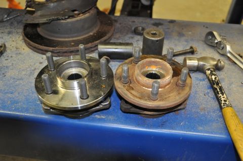 1996 Ford Bronco - Comparing a new wheel hub to a rusty old one, with a brake rotor and tools nearby.