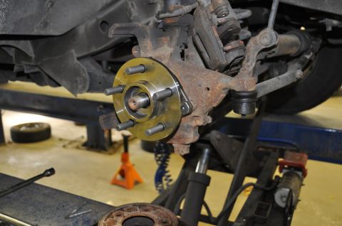 1996 Ford Bronco - Close-up of a vehicle's front wheel hub assembly undergoing repair, with suspension parts visible.
