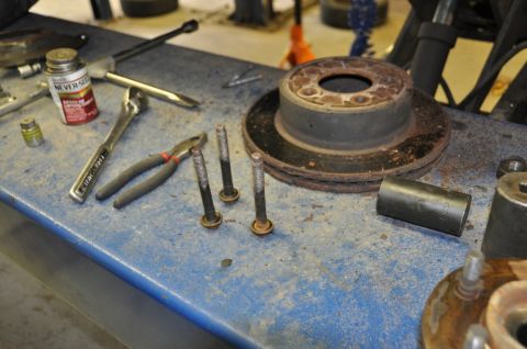 1996 Ford Bronco - Tools and a brake rotor are laid out on a workbench, suggesting a vehicle repair or maintenance task.