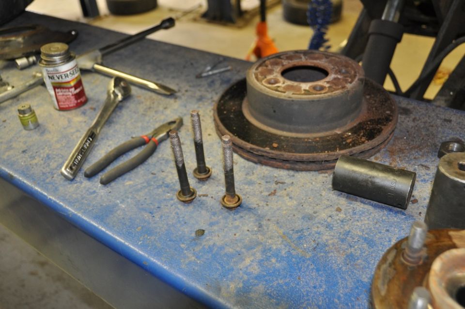 Brake rotor and lug bolts on a workbench with tools
