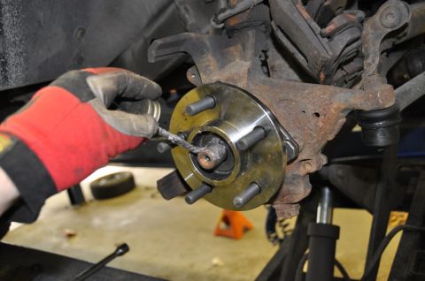 1996 Ford Bronco - Mechanic applies grease to a new wheel hub assembly during a vehicle repair.