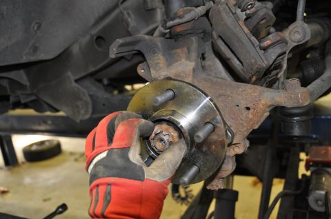 1996 Ford Bronco - Mechanic works on replacing a wheel hub assembly on a vehicle's suspension.