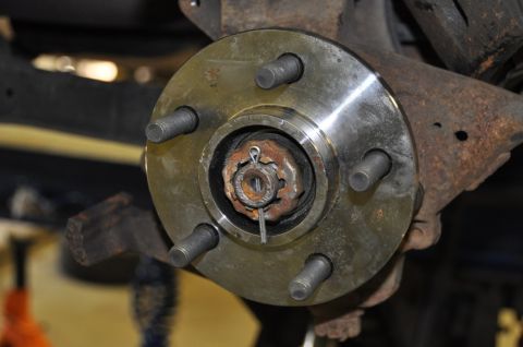 1996 Ford Bronco - This is a close-up view of a vehicle's wheel hub assembly, showing the lug bolts and the castle nut with its cotter pin.