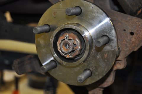 1996 Ford Bronco - A close-up view of a vehicle's wheel hub assembly, showing the lug studs and castle nut.