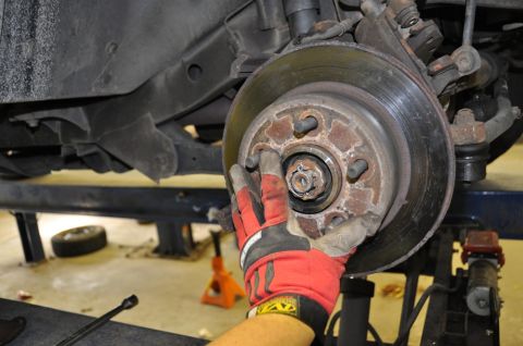 1996 Ford Bronco - Mechanic's gloved hand inspects a worn wheel hub assembly during a repair.
