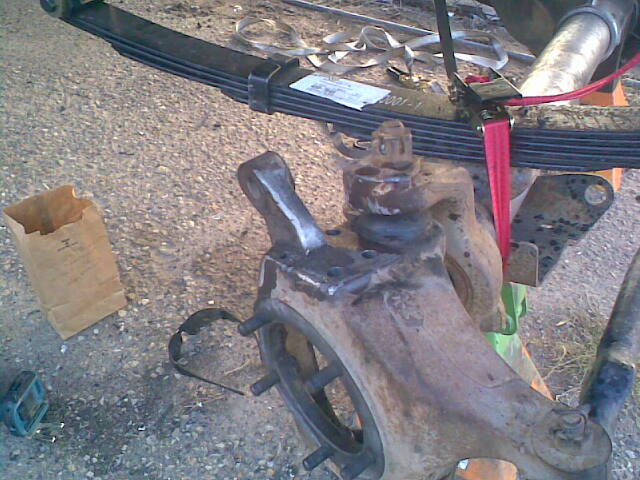 close-up of a rusty vehicle suspension component with leaf springs above
