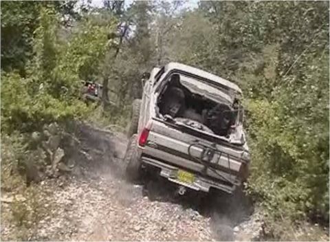 1996 Ford Bronco - A 1996 Ford Bronco navigates a dusty, off-road trail with another vehicle visible in the distance.