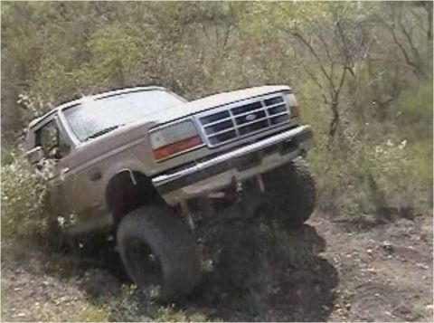 1996 Ford Bronco - Ford Bronco navigating a steep, overgrown incline with its front wheels turned.