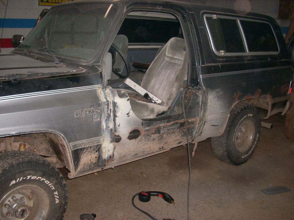 Black 1988 Chevrolet K5 Blazer driver's side during restoration, showing rust and repair.