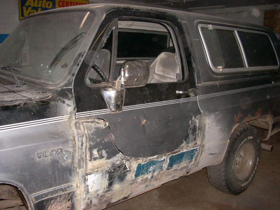 Black 1988 Chevrolet Blazer driver's side door with body damage and repair work.