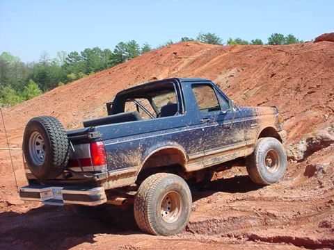 1989 Ford Bronco - Muddy 1989 Ford Bronco navigates a steep, sandy incline.