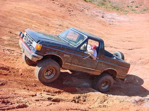 1989 Ford Bronco - This Ford Bronco is navigating a challenging off-road terrain with steep inclines and loose dirt.