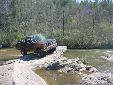 1989 Ford Bronco - Ford Bronco navigates rocky terrain near a river.