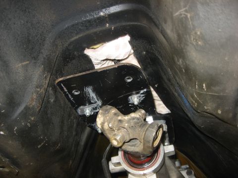 1978 Ford Mustang II - A black metal bracket is bolted to the underside of a vehicle, with a universal joint visible below it. A white cloth is tucked into the ca…