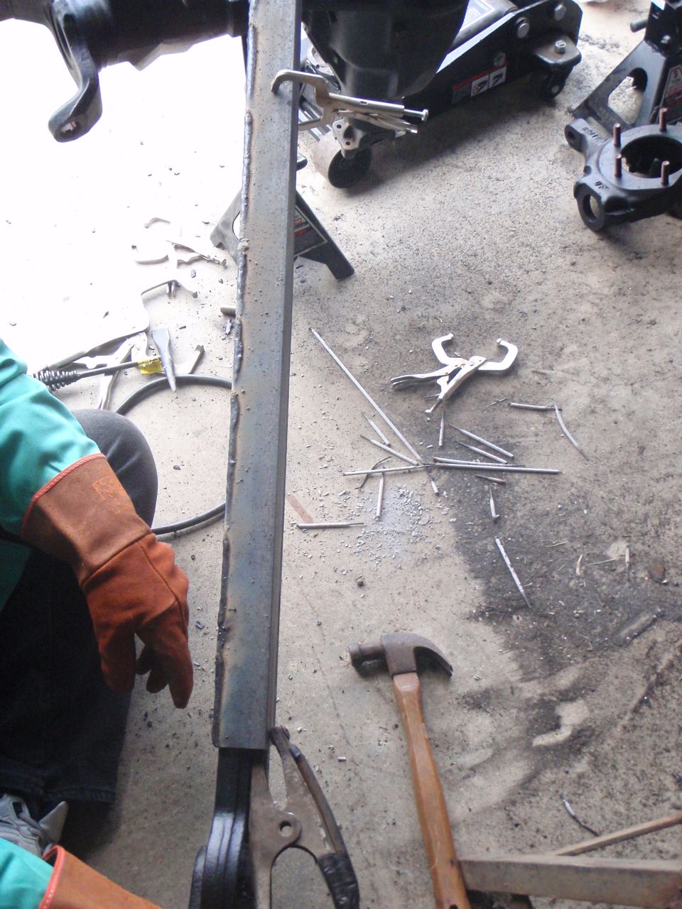 Welding clamps, a hammer, and metal rods scattered on a concrete floor.