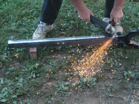 1996 Ford Bronco - A person is using an angle grinder to cut a metal bar, creating a shower of sparks. The bar is supported by a small wooden block on the gro…
