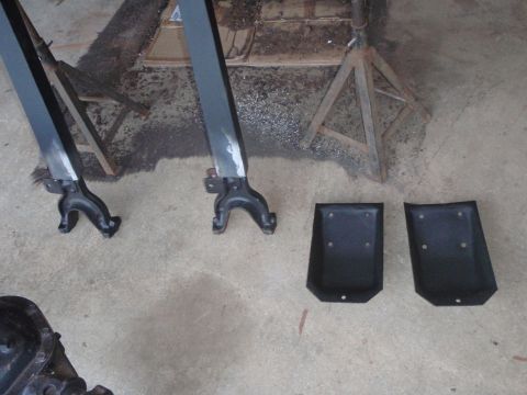 1996 Ford Bronco - Two black metal brackets with four mounting holes each are shown on a concrete floor, next to two black metal jack stands. A portion of a v…