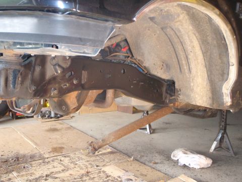 1996 Ford Bronco - The underside of a vehicle, likely a 1996 Ford Bronco, is shown supported by jack stands. The frame, suspension components, and a portion o…