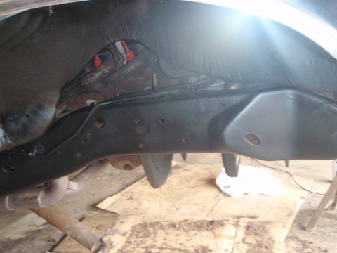 1996 Ford Bronco - Underneath view of a dark-colored vehicle frame, likely from a 1990s Ford Bronco, with what appears to be a freshly applied protective coat…