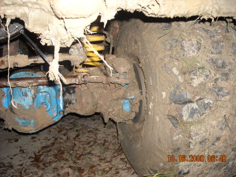 1979 Ford Bronco - Close-up view of a heavily mud-caked vehicle suspension and tire, obscuring specific details.