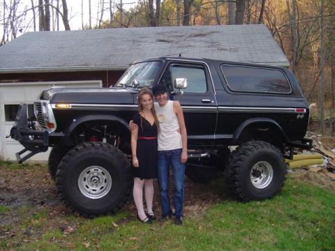 1991 Ford Bronco - A couple poses with a heavily modified black Ford Bronco, large off-road tires and a lifted suspension.