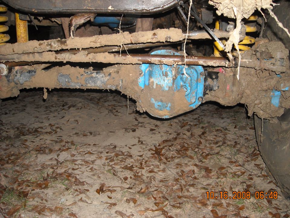 Mud-covered front axle, differential, and suspension parts of an off-road vehicle