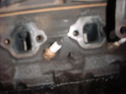 1989 Ford Bronco - Close-up of an engine block showing a spark plug and exhaust ports.