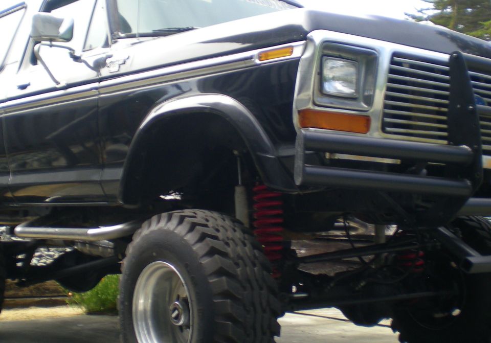 Black 1978 Ford Bronco front fender and grille with aftermarket bumper and red suspension components