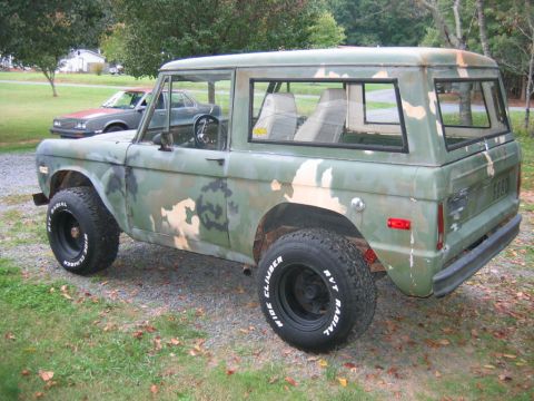1992 Ford Mustang - A vintage early Ford Bronco 4x4 wearing a green, tan and brown camouflage paint job, shown from the rear 3/4 side angle with the top on and…