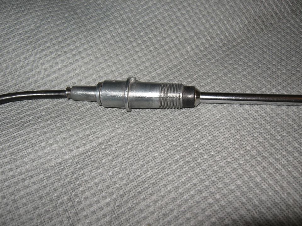 Metal antenna base with ribbed section and cable attached, on a textured gray surface