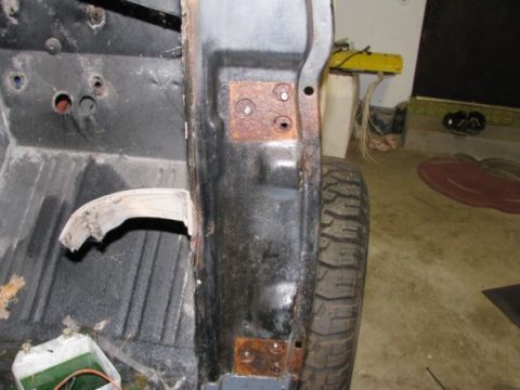 1976 Ford Bronco - Close-up of a rusted vehicle body panel and tire, likely undergoing restoration.