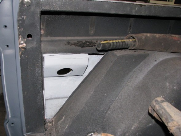 Vehicle interior showing a metal bracket with a hole and a rubber hose inside a metal tube