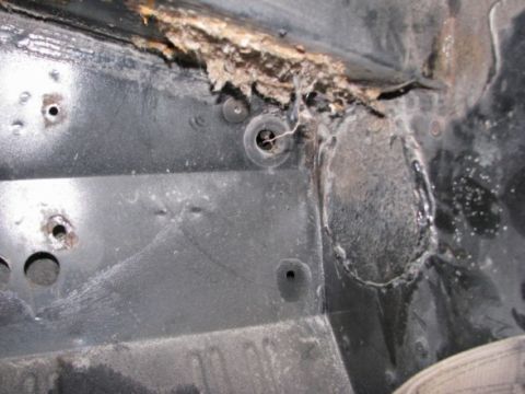1976 Ford Bronco - This close-up shows significant rust and damage to a vehicle's frame, indicating structural compromise.