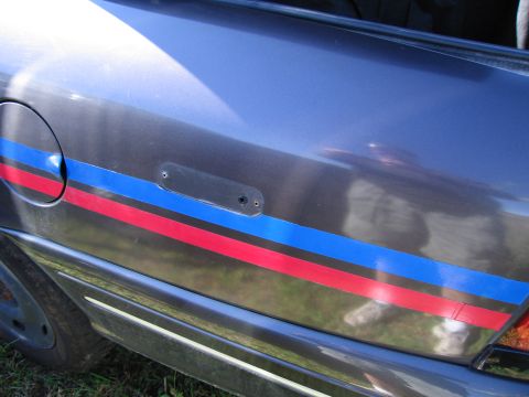 1991 Ford LTD Crown Victoria - A close-up of a car's side panel reveals red and blue racing stripes along the door.