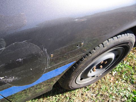 1991 Ford LTD Crown Victoria - Close-up of a car's side panel and wheel, showing damage and a blue stripe.