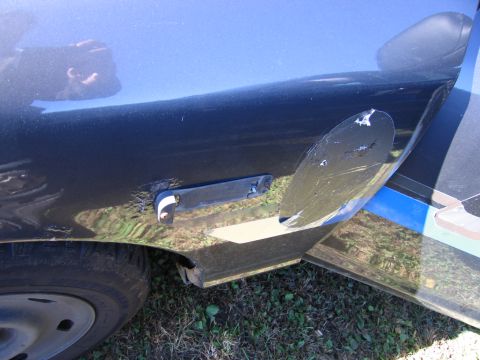 1991 Ford LTD Crown Victoria - The rear quarter panel and door of a car show significant damage, including scratches, dents, and rust around a removed trim piece.
