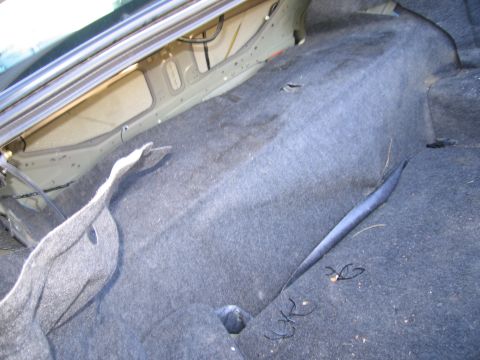 1991 Ford LTD Crown Victoria - The trunk of a car is shown with the carpet removed, revealing the underlying structure and wiring.