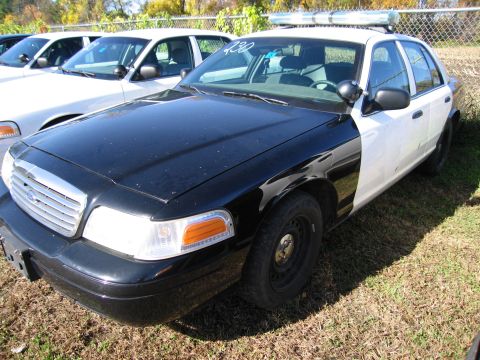1991 Ford LTD Crown Victoria - A black and white police car, identified as a 1991 Ford Crown Victoria LTD, is parked outdoors with other vehicles.