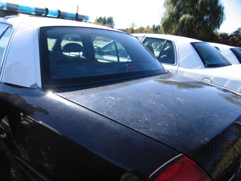 1991 Ford LTD Crown Victoria - Rear view of a black police car, showing its trunk and part of the light bar on the roof.