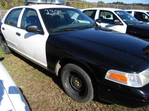 1991 Ford LTD Crown Victoria - A two-tone police car is parked outdoors with other vehicles visible in the background.