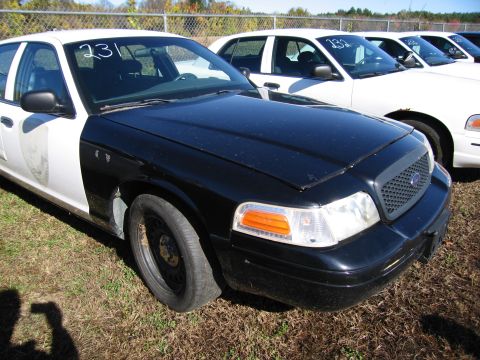 1991 Ford LTD Crown Victoria - A black and white police car is parked in a lot with other vehicles visible behind it.