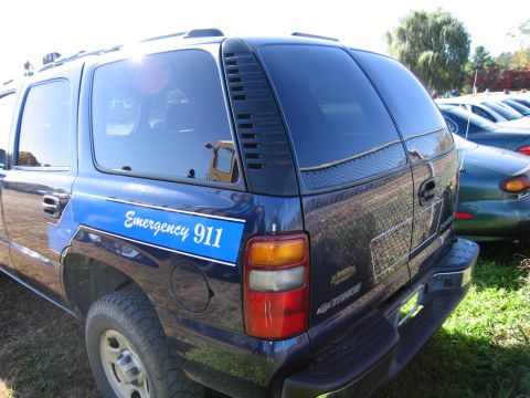 1991 Ford LTD Crown Victoria - A blue SUV, possibly a Chevrolet Tahoe, displays "Emergency 911" text on its side, parked next to other vehicles.