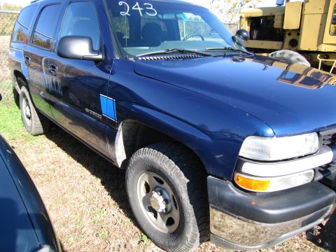 1991 Ford LTD Crown Victoria - A blue SUV is parked on a grassy lot, with a yellow construction vehicle in the background.