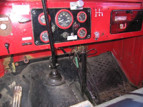 1991 Ford LTD Crown Victoria - The interior of a vehicle shows a red dashboard with multiple gauges and a floor with pedals and a gear shift lever.