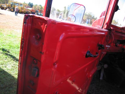 1991 Ford LTD Crown Victoria - Interior view of a red truck door, showing the handle and hinges, with construction equipment in the background.