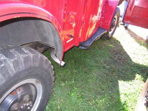 1991 Ford LTD Crown Victoria - Close-up view of the side of a red truck, showing its large tire, exhaust pipe, and running board.