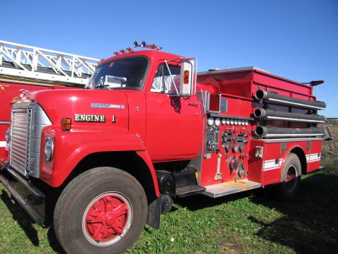 1991 Ford LTD Crown Victoria - A bright red fire engine is parked outdoors under a clear blue sky.