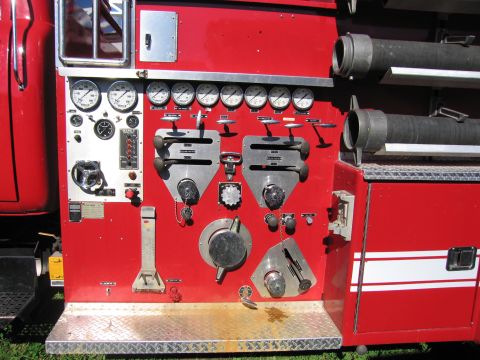 1991 Ford LTD Crown Victoria - Close-up of a red fire truck's control panel, multiple gauges and operational levers.